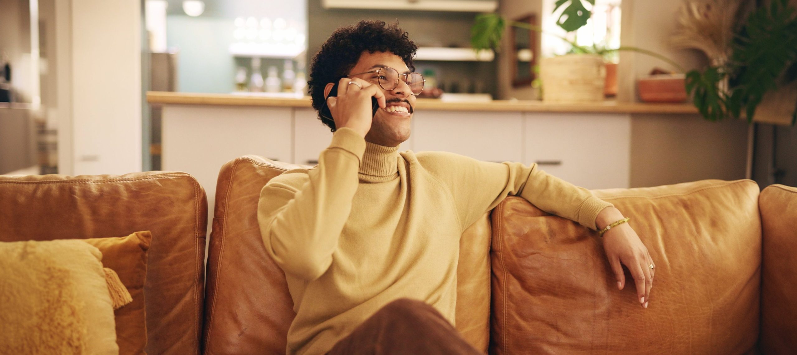 A smiling man on a phone call on his sofa